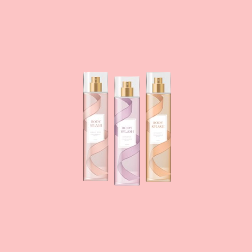 Three body splash bottles in pink, purple, and peach tones are placed side by side on a solid light pink background.